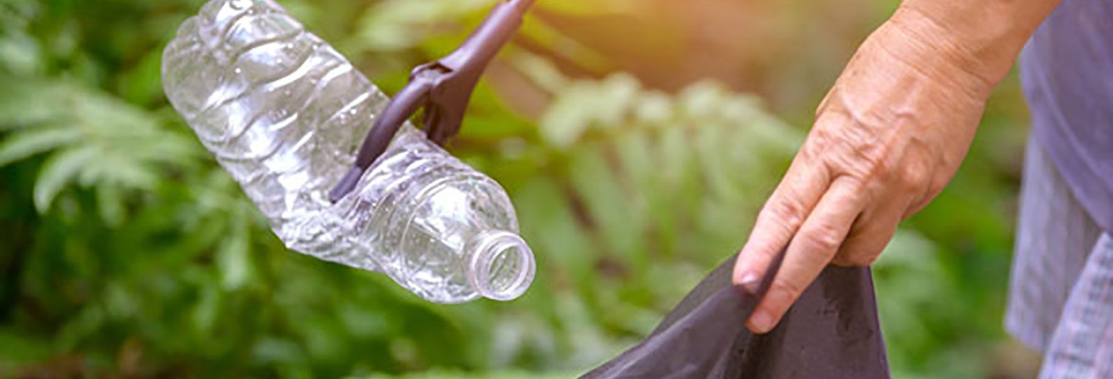 Person placing plastic bottle in a bin bag banner image