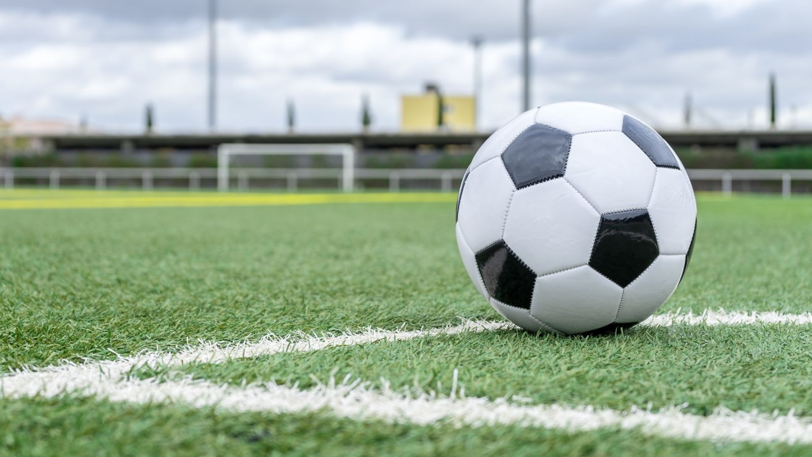 Close up of a black and white fooball on a green pitch banner image