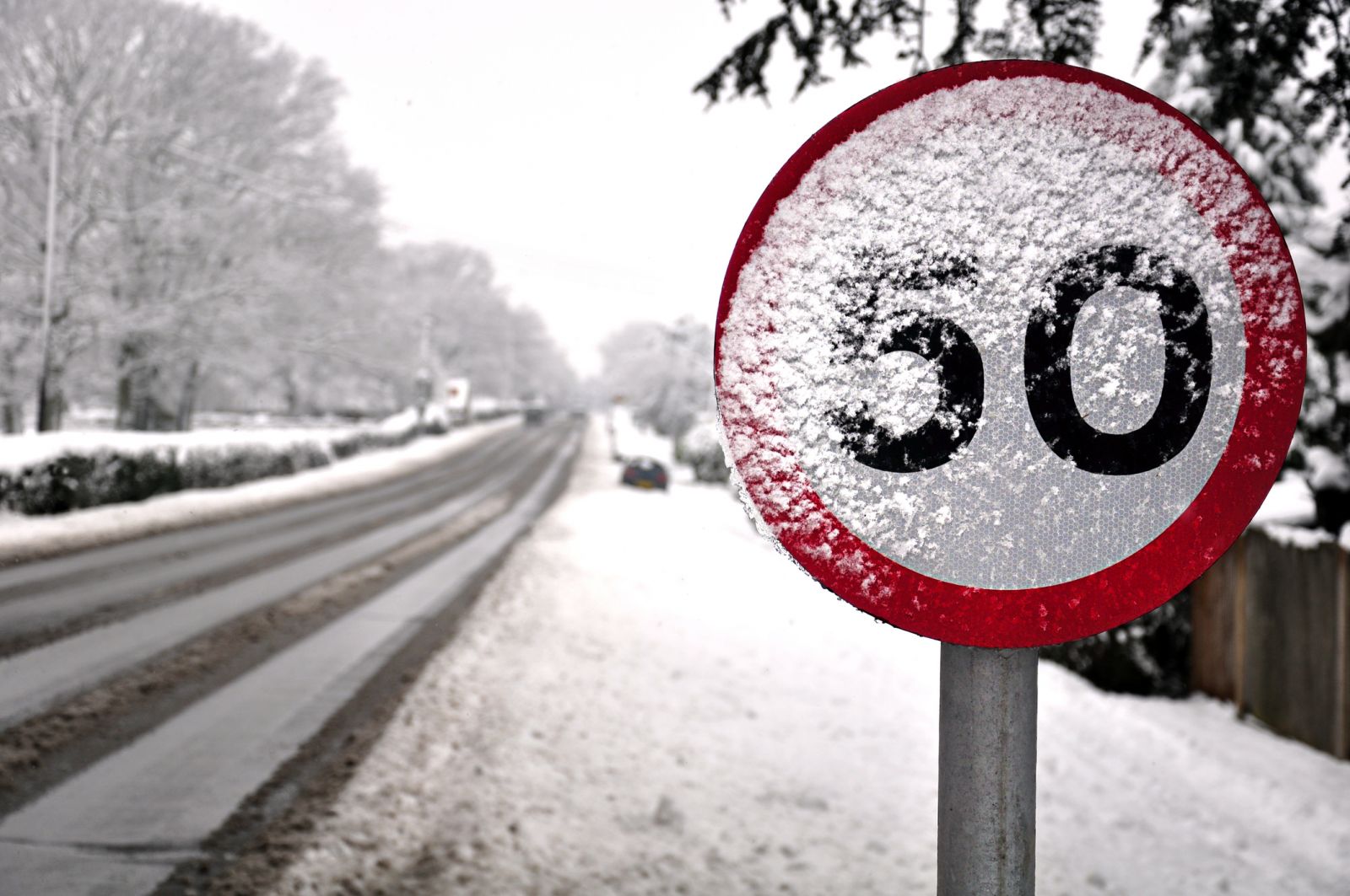 50mph speed limit sign partially covered in snow, with a snowy carriageway in the rear banner image